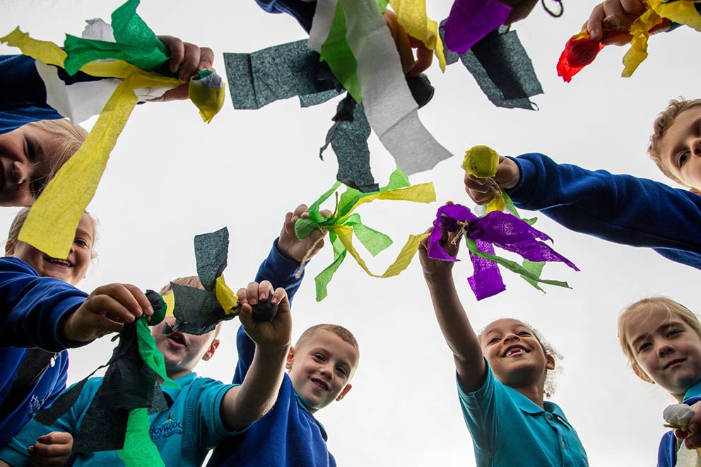 School pupils in a circle showcasing their crafts.